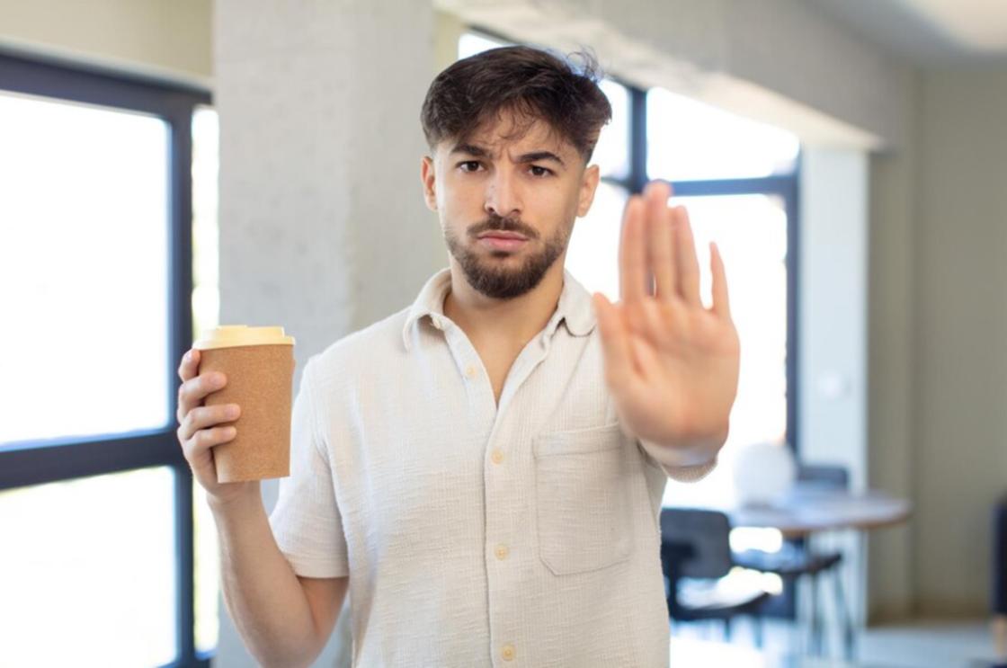 Мужчина со стаканом кофе делает жест рукой