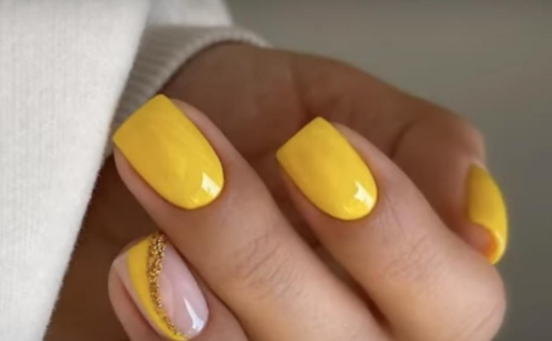 Желтый лак на коротких квадратных ногтях с добавлением волнистых линий и блесток