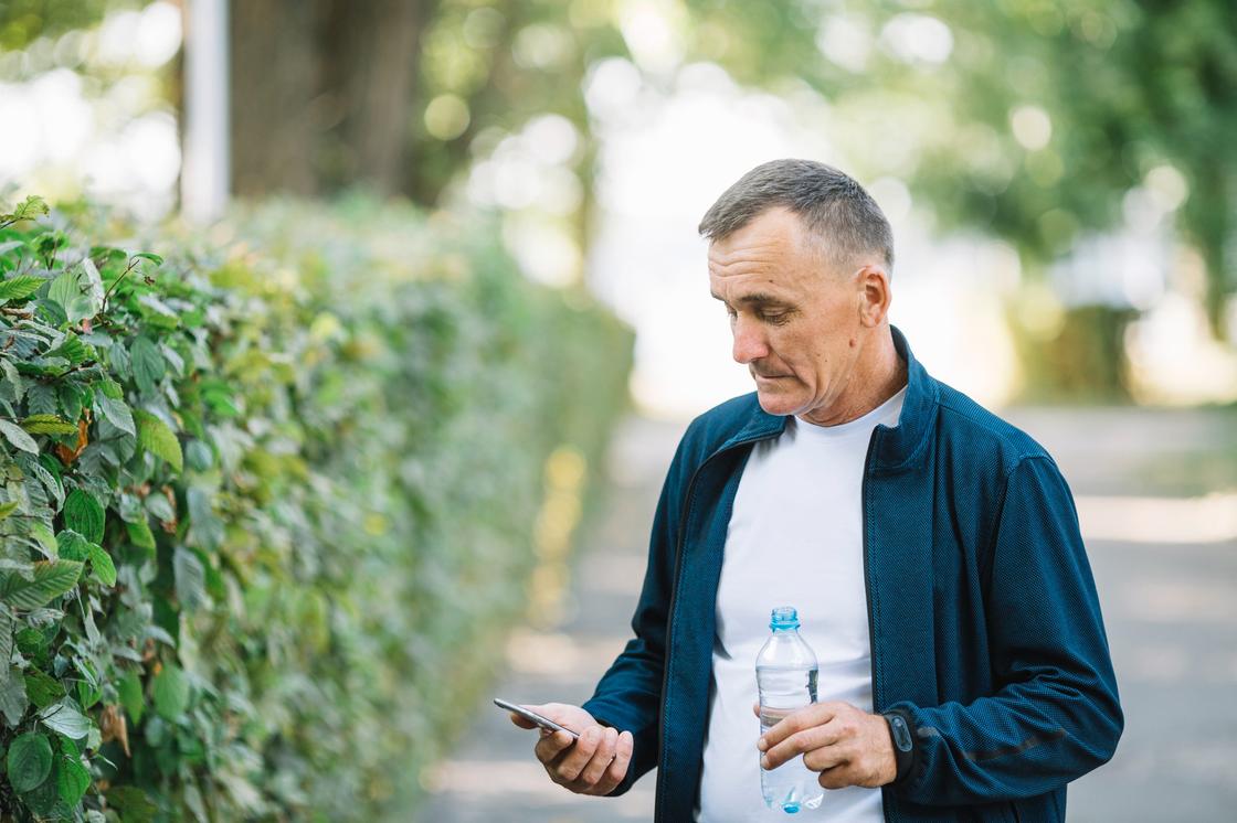 Мужчина с телефоном и бутылкой воды