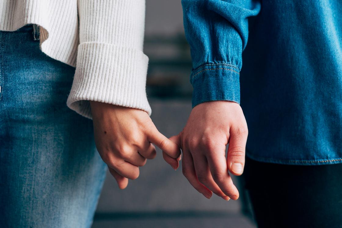 Мужчина и женщина держатся за руки мизинцами