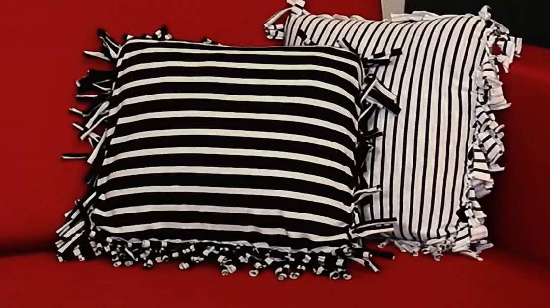 На диване лежат две декоративные подушки из полосатых футболок. Края подушек завязаны на узелки