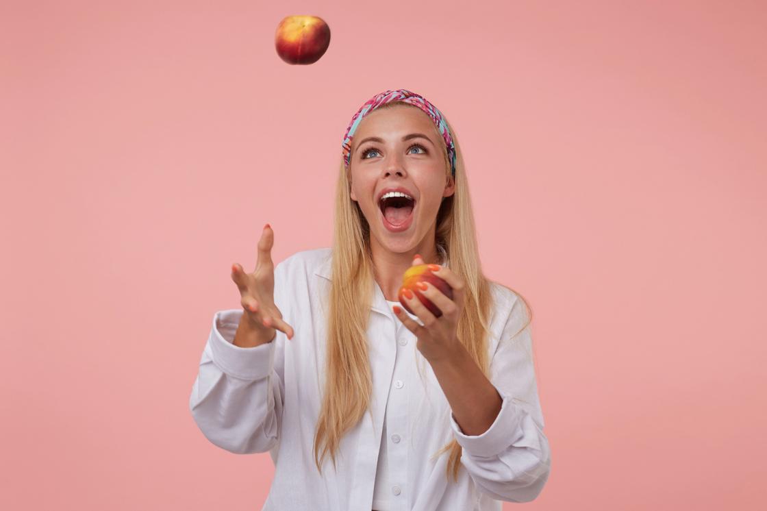 Девушка жонглирует двумя персиками