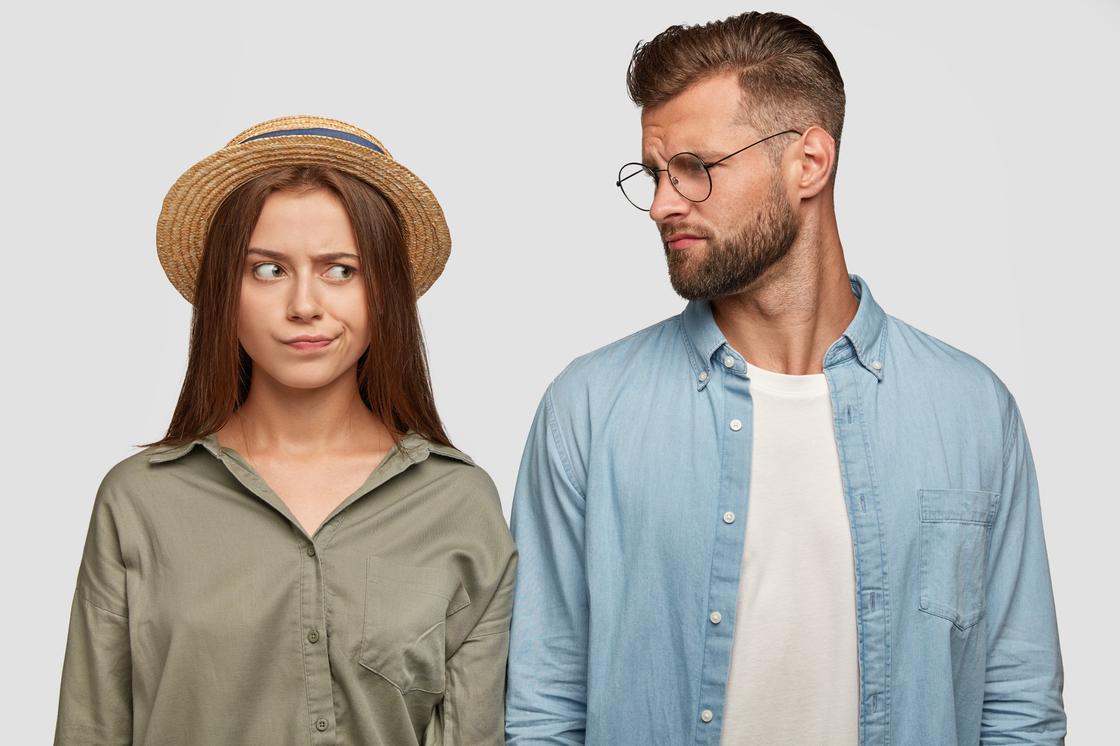 Женщина в шляпе и мужчина в очках с недовольными лицами