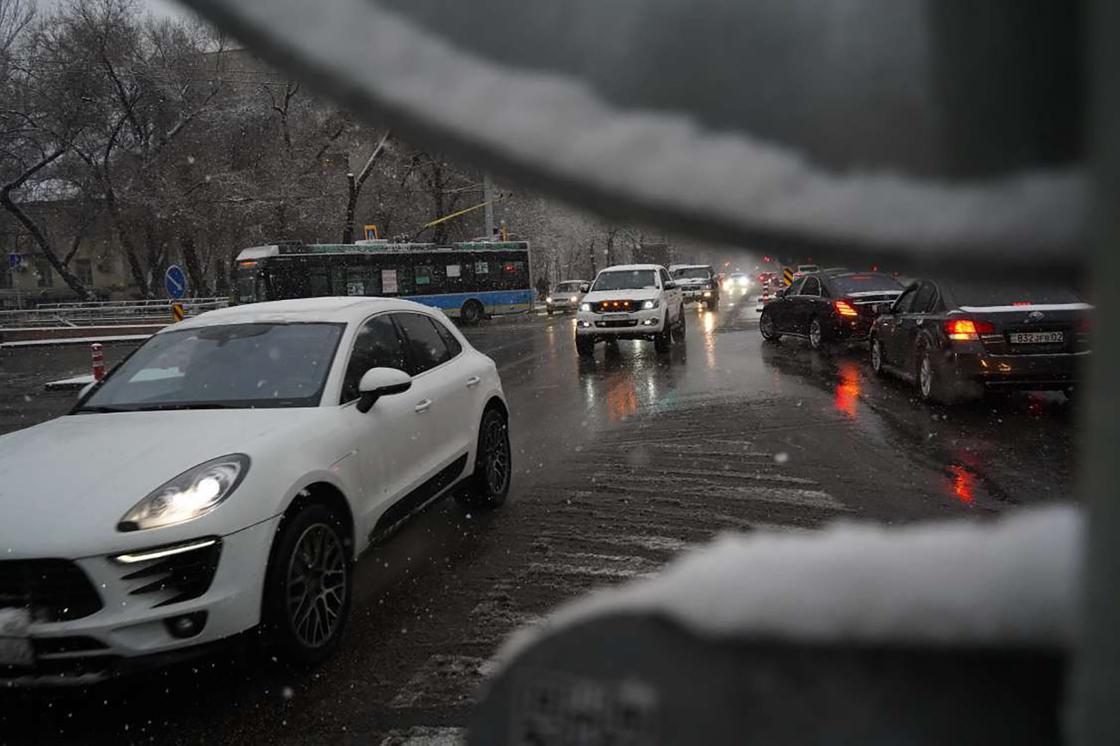 Машины едут по дороге в снегопад