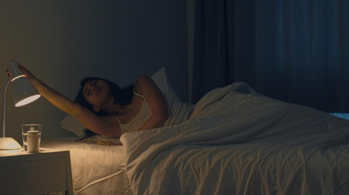 Девушка выключает ночник возле кровати