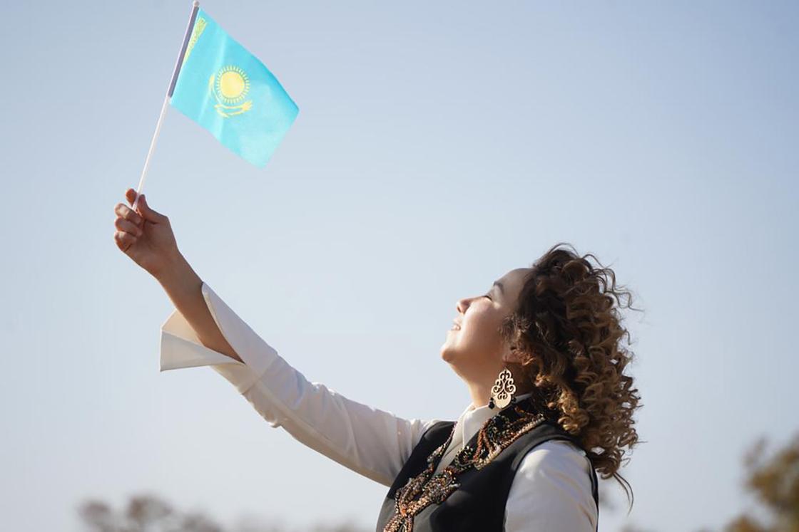 Девушка держит флаг Казахстана на фоне неба