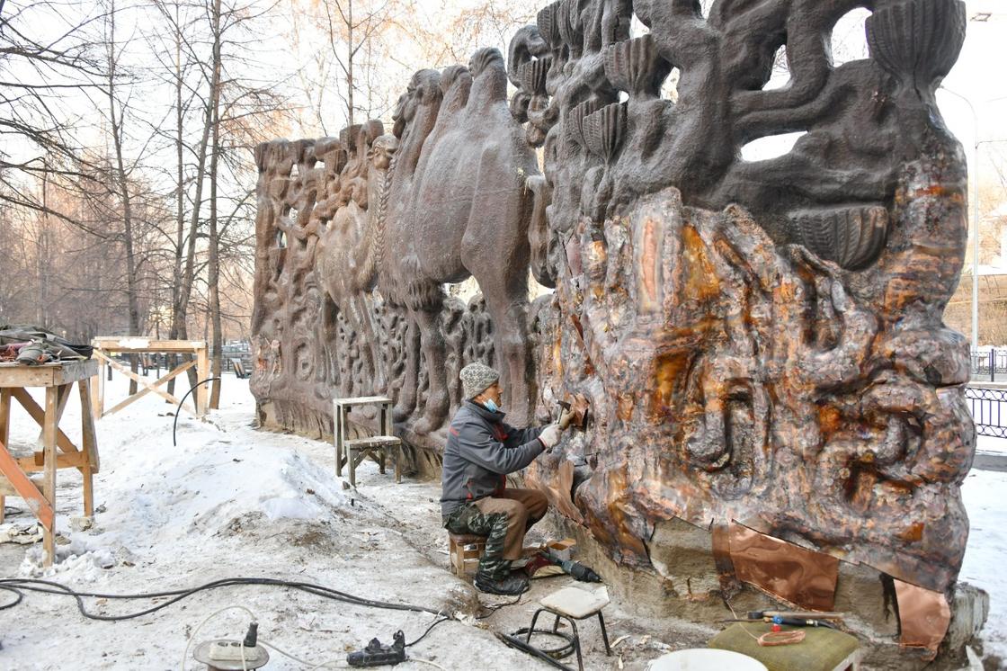Рабочий реставрирует панно "Верблюды" в Алматы
