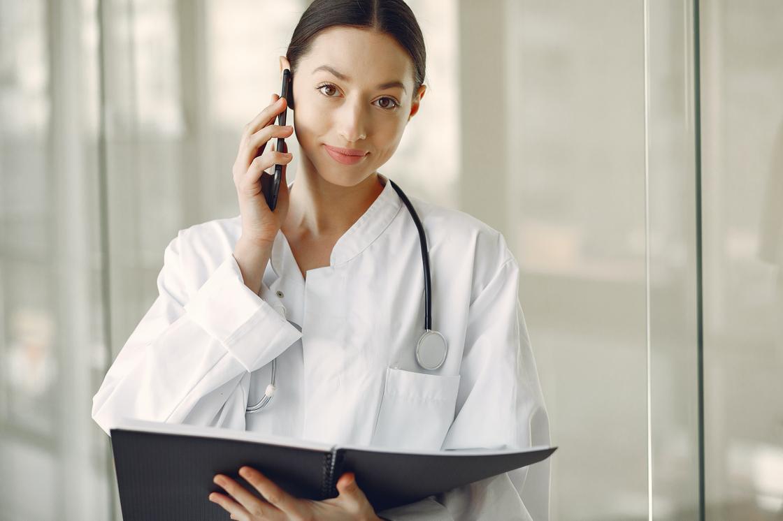 Девушка-врач с телефоном и папкой в руках