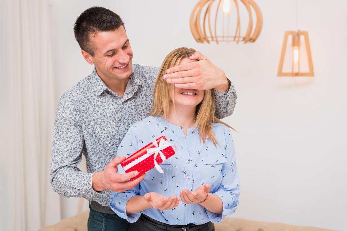 Мужчина с подарком в руках закрыл глаза женщине