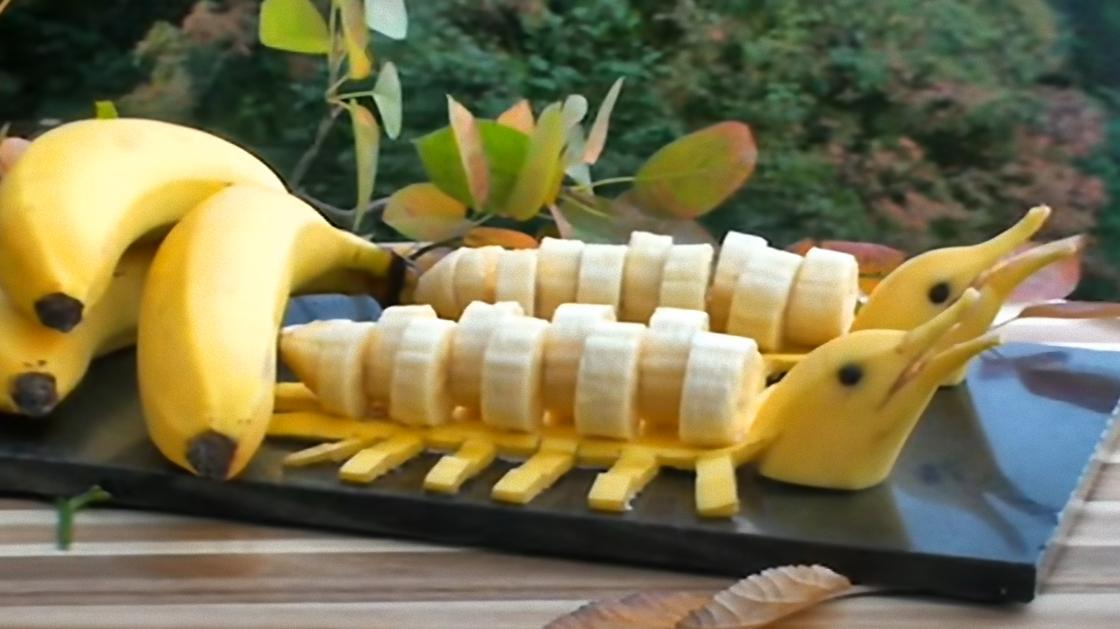 На столе лежат целые бананы и разрезанные два банана в форме дельфинов