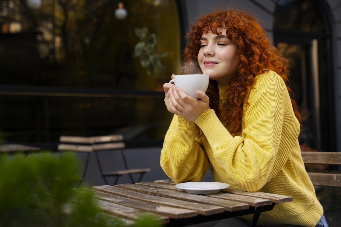 Девушка пьет кофе за столиком на улице