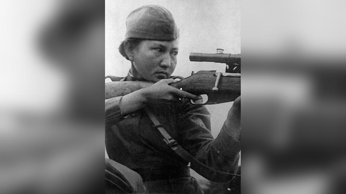 Алия Молдагулова держит в руках винтовку