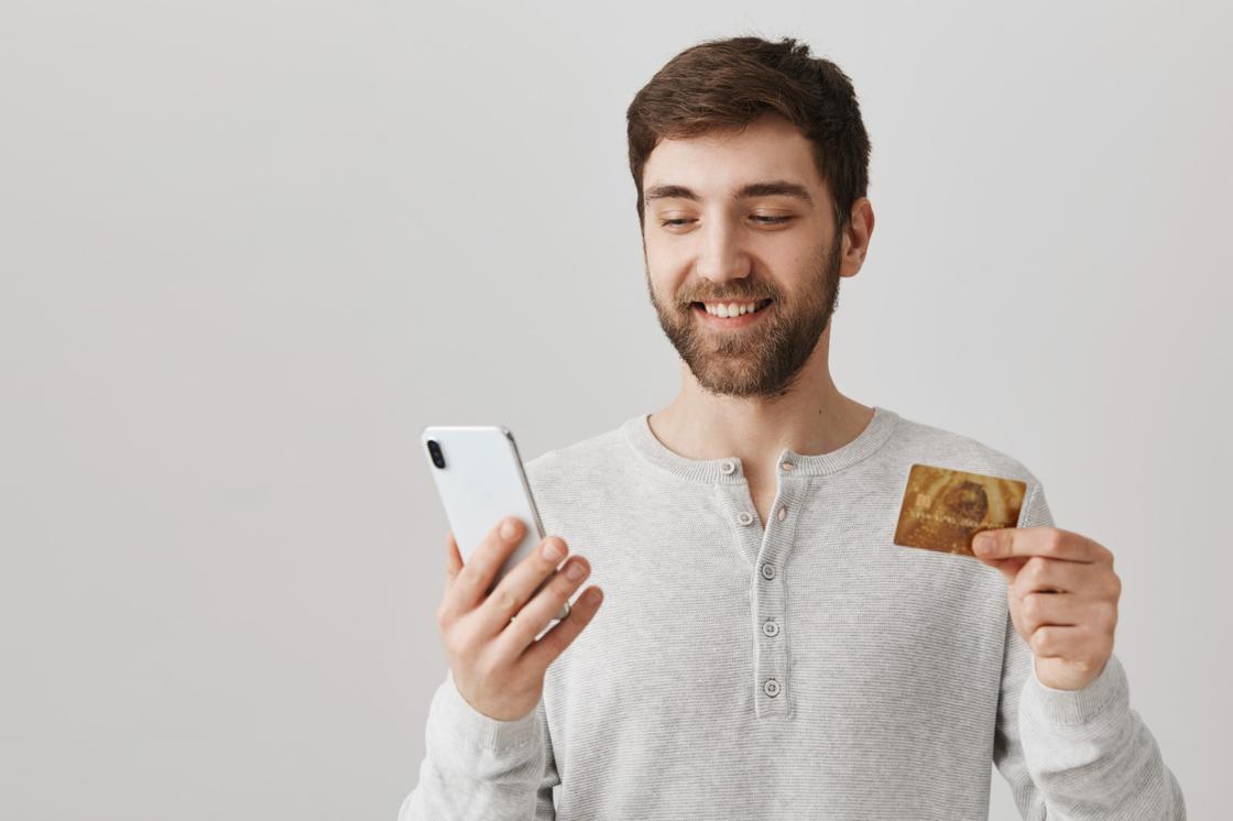Мужчина держит телефон и банковскую карту
