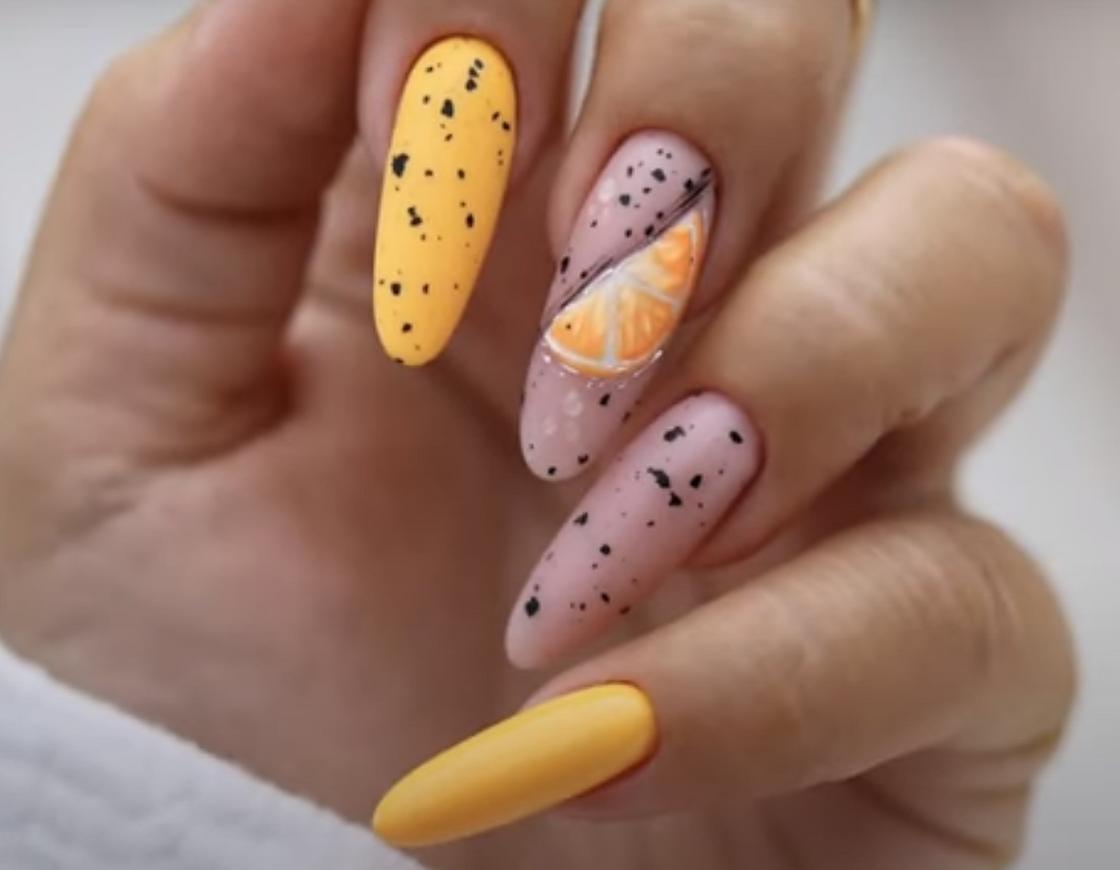Длинные миндалевидные ногти, украшенные желтым и нюдовым лаком с принтом перепелиное яйцо и рисунком дольки апельсина