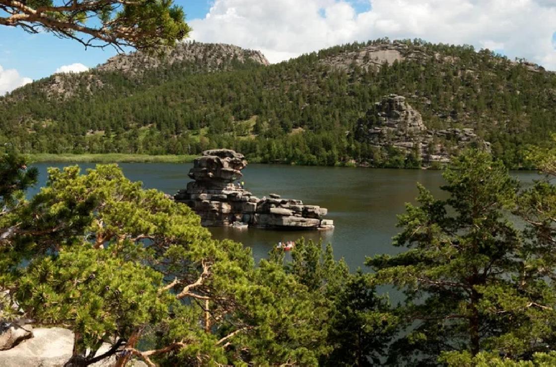 Скала в озере, горы, поросшие лесом