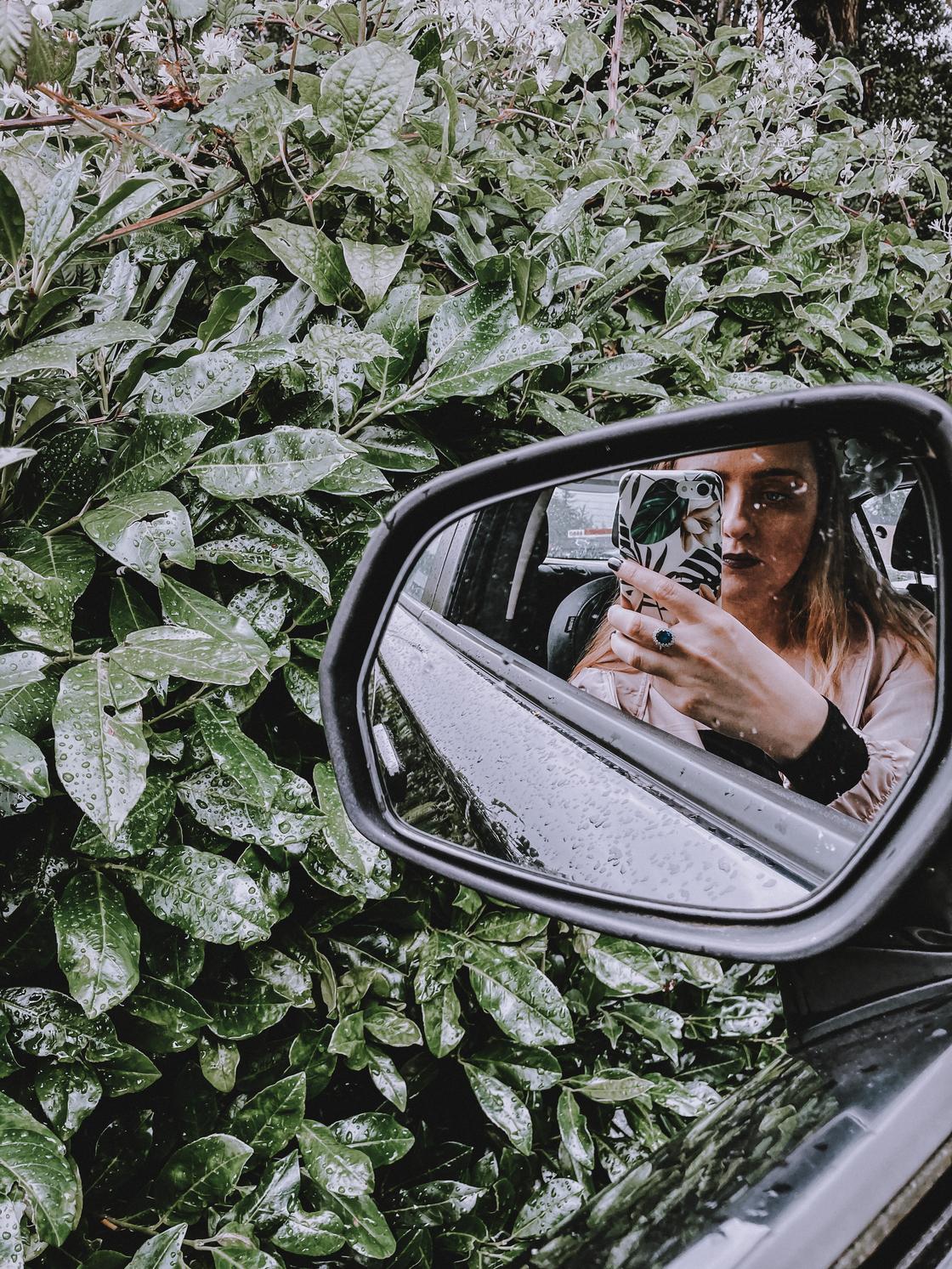 Девушка делает селфи в зеркале автомобиля