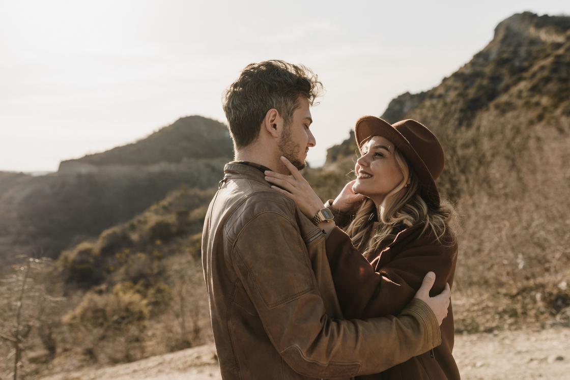 Мужчина и женщина обнимаются на фоне холмистого пейзажа