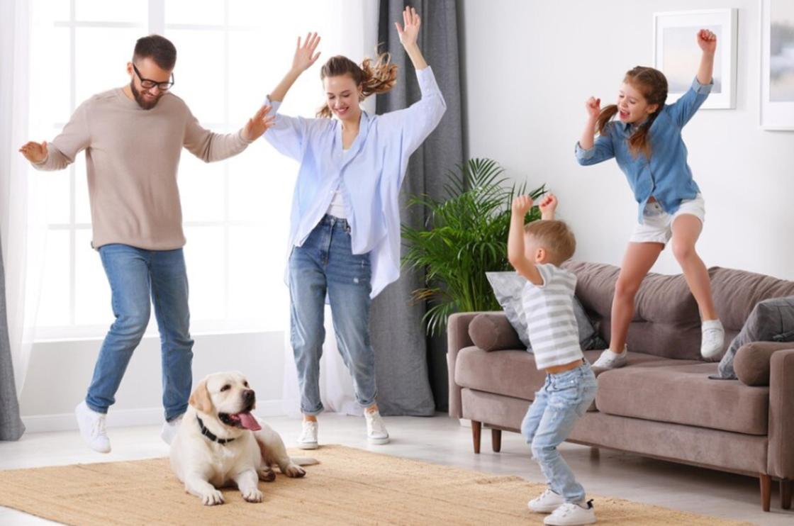 Семья с детьми и собакой прыгает от радости
