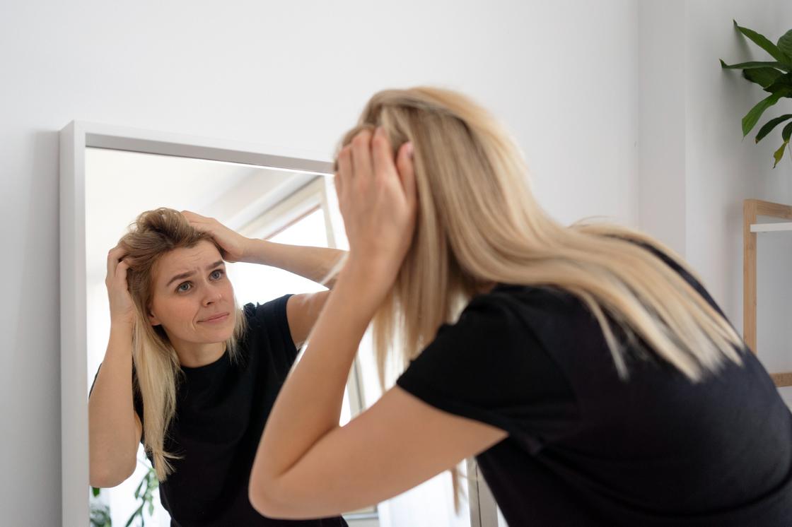 Женщина с беспокойством рассматривает себя с зеркалом