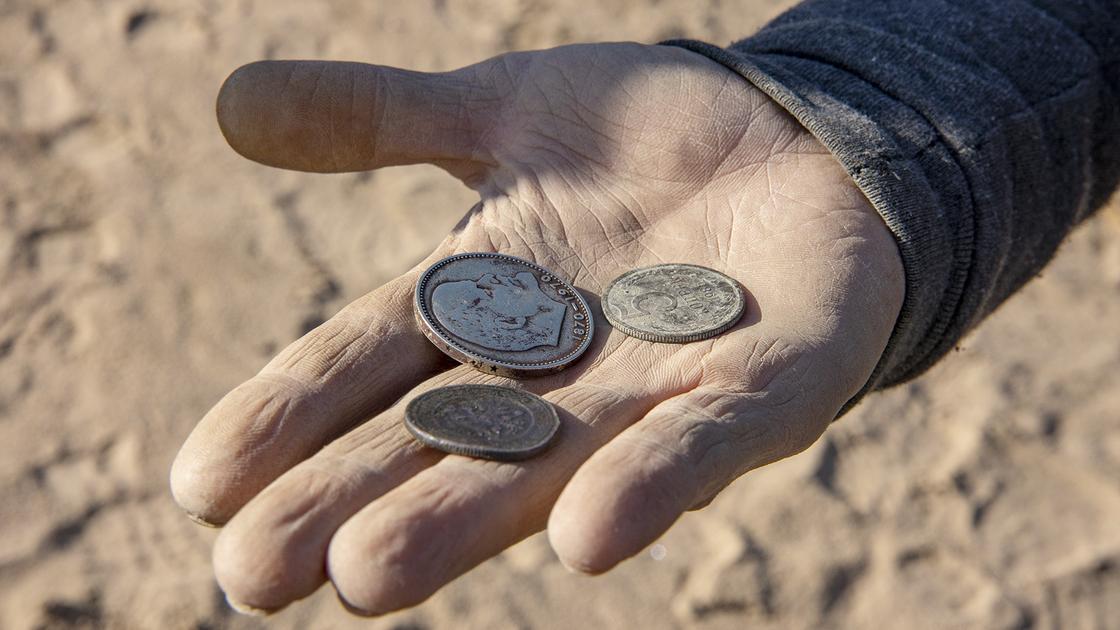 мужчина держит в руке старые монеты