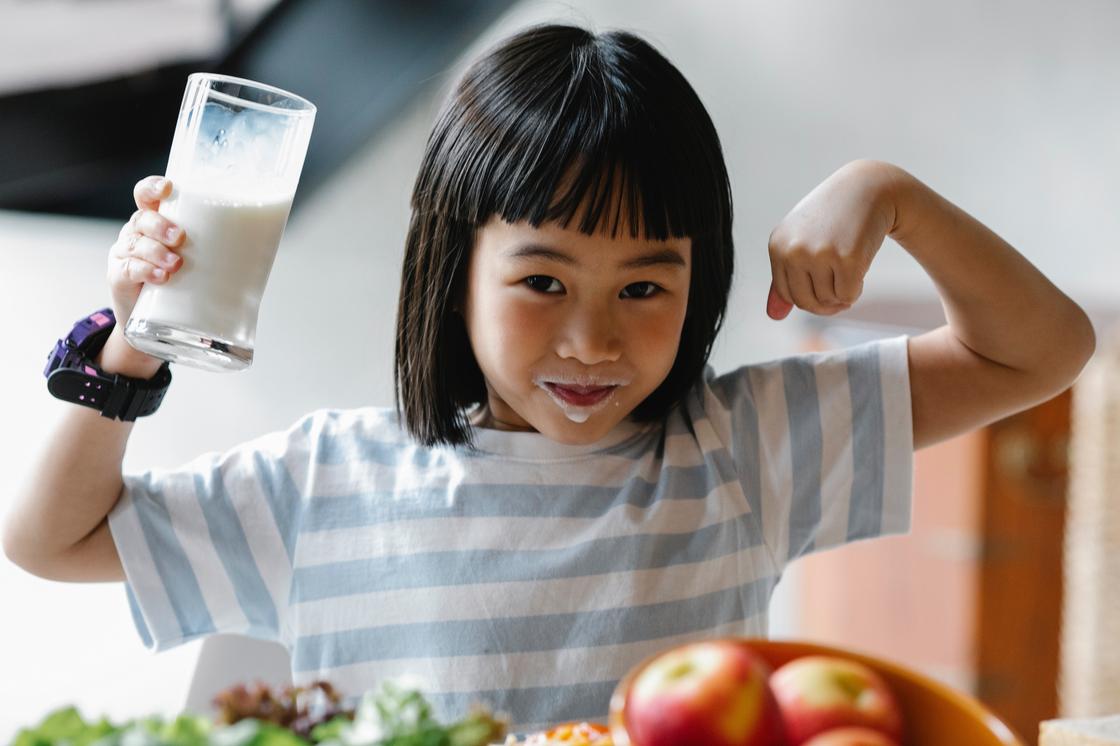 Девочка держит стакан молока