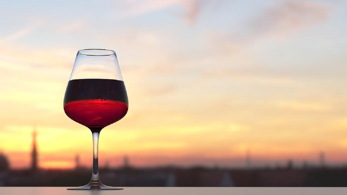 Красное вино в бокале на фоне заката