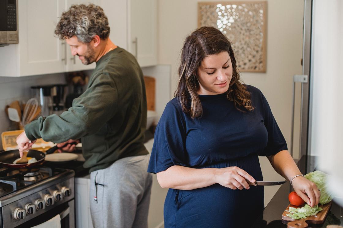 Беременная женщина готовит еду вместе с мужчиной