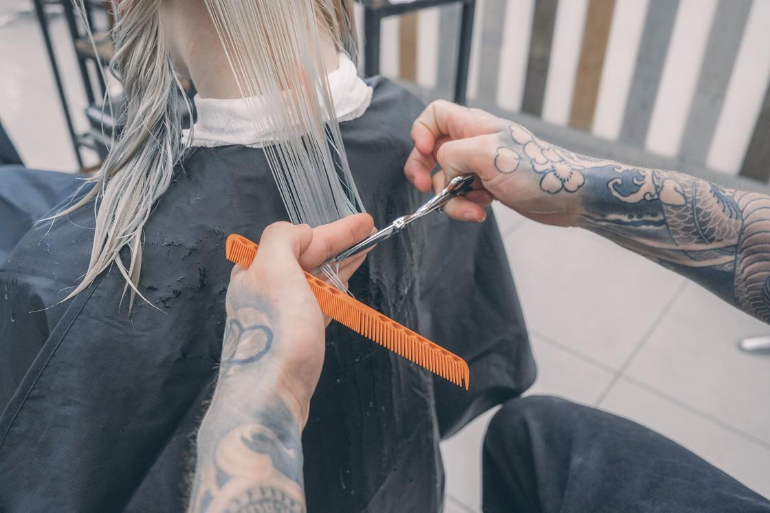 Парикмахер стрижет кончики волос