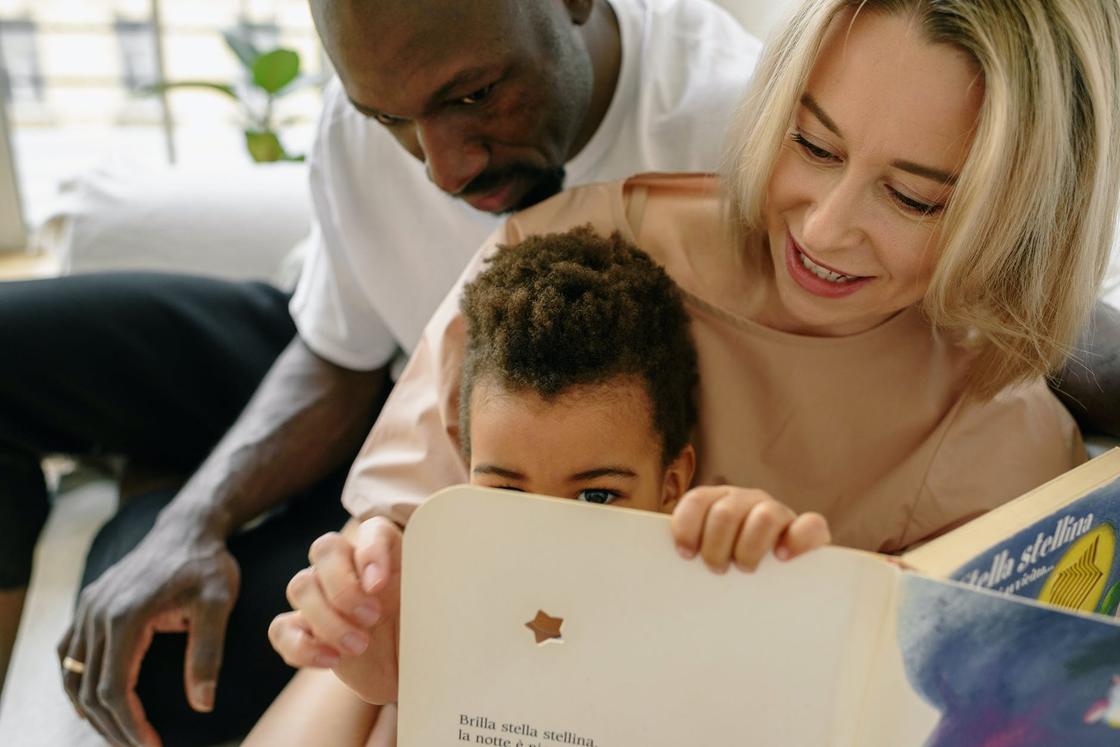 Ребенок читает книгу вместе с родителями