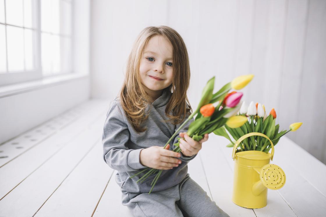 Девочка держит в руках букет тюльпанов