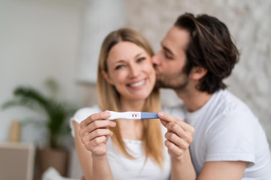 Мужчина и женщина держат в руках позитивный тест на беременность