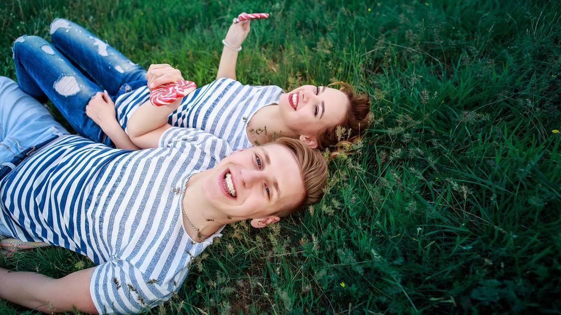 Смеющиеся девушка и парень лежат на траве