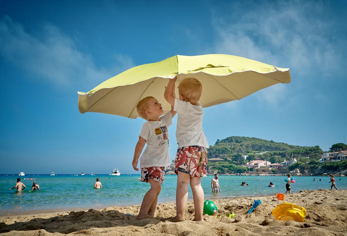 Дети на пляже под зонтом