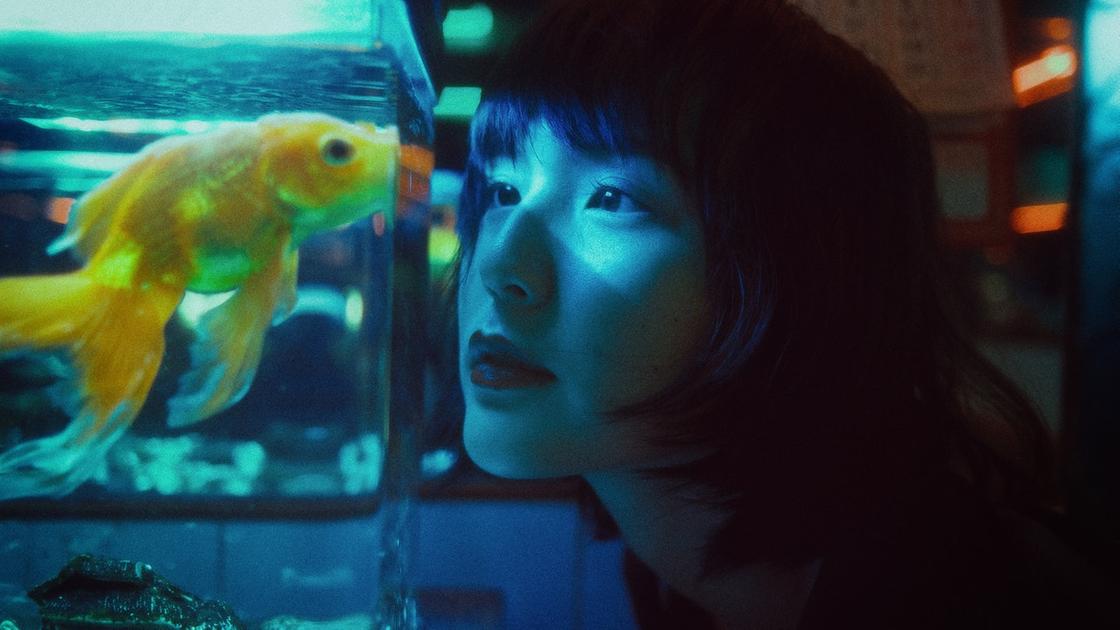 Девушка смотрит на рыбку в аквариуме