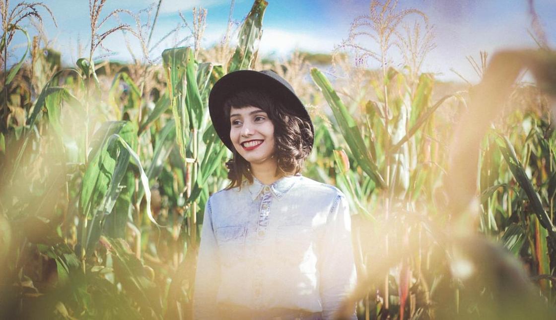 Девушка стоит на кукурузном поле