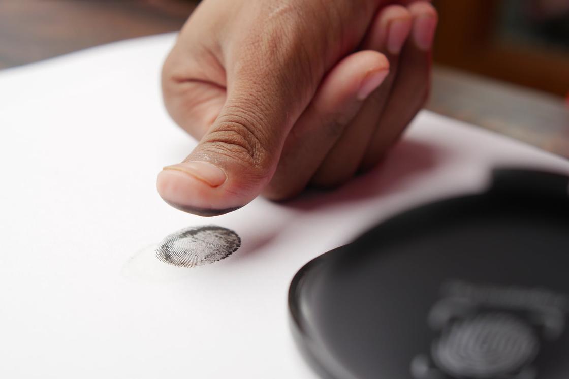 Человек оставляет отпечаток пальца на бумаге