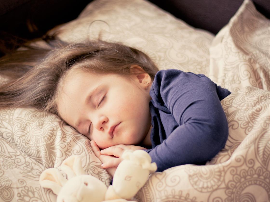 Маленькая девочка спит в постели