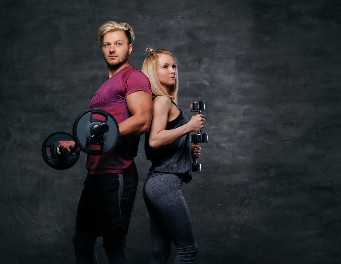 Мужчина и женщина спортивного телосложения с гантелями