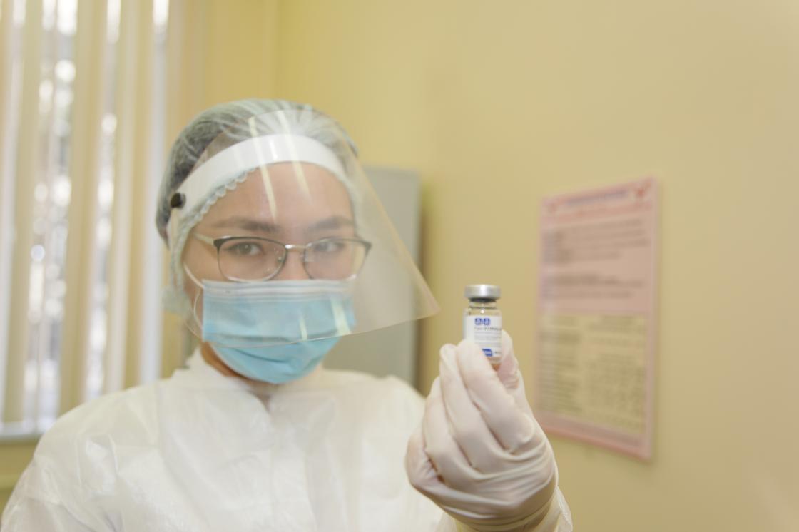 Медик держит в руке ампулу с вакциной от КВИ