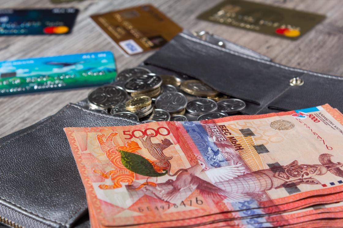 На столе лежат деньги, монеты и банковские карты