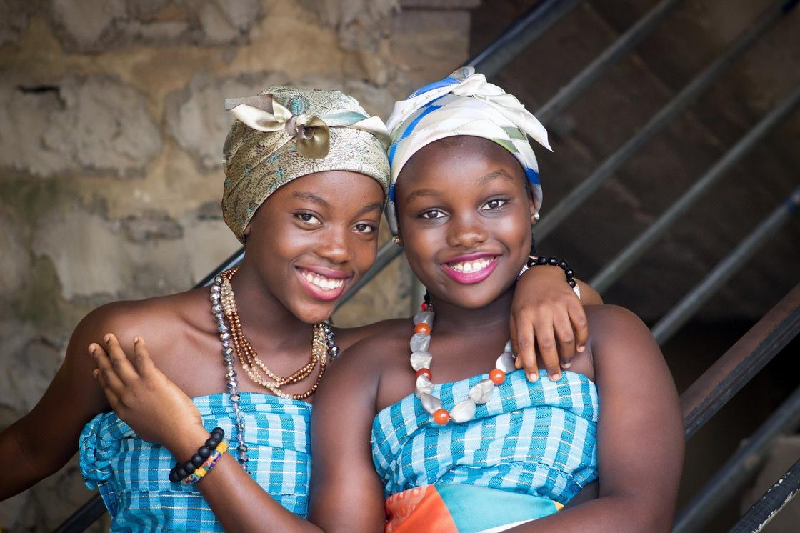 Две африканские женщины сидят, обнимая друг друга