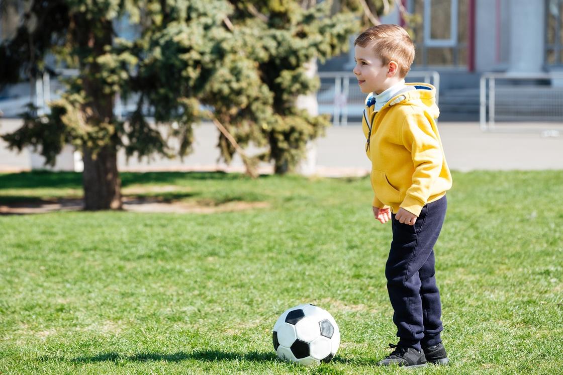 Мальчик пинает футбольный мяч