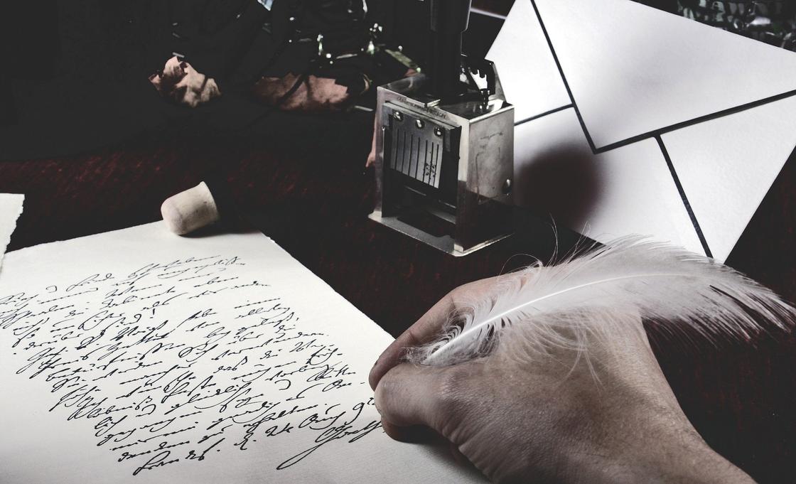 Мужчина пишет пером на листе