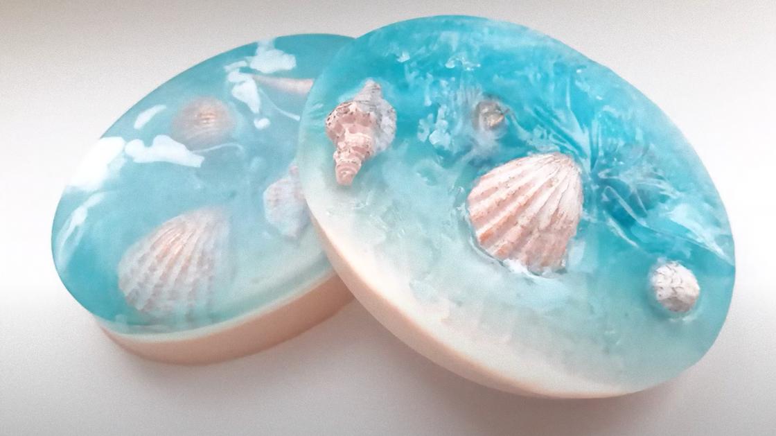Два круглых кусочка мыла в морском стиле с ракушками на поверхности