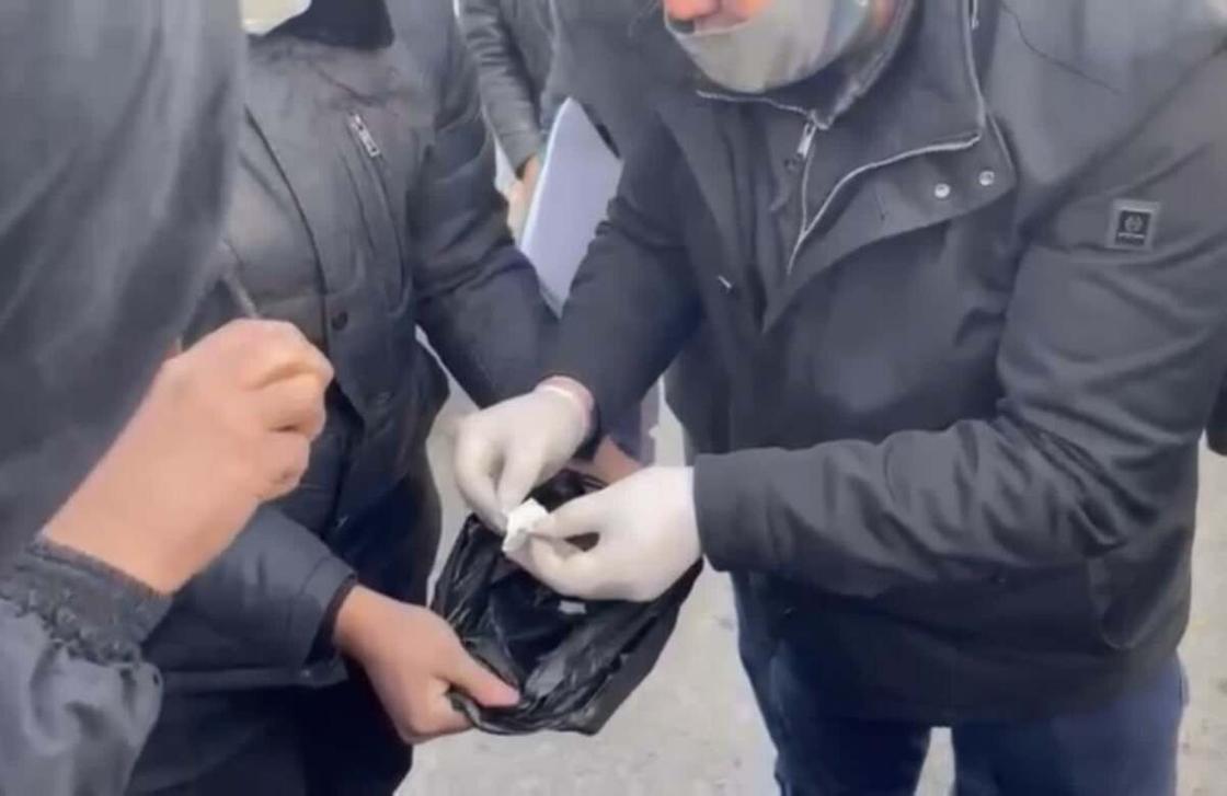 полицейский достает из черного пакета сверток