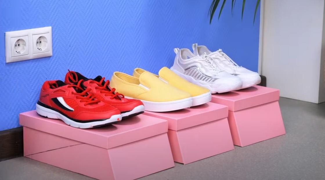 На розовых картонных коробках стоят разноцветные пары спортивной обуви