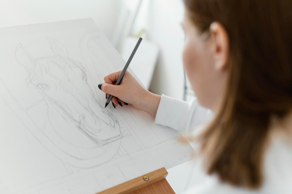 Девушка рисует простым карандашом на холсте коня