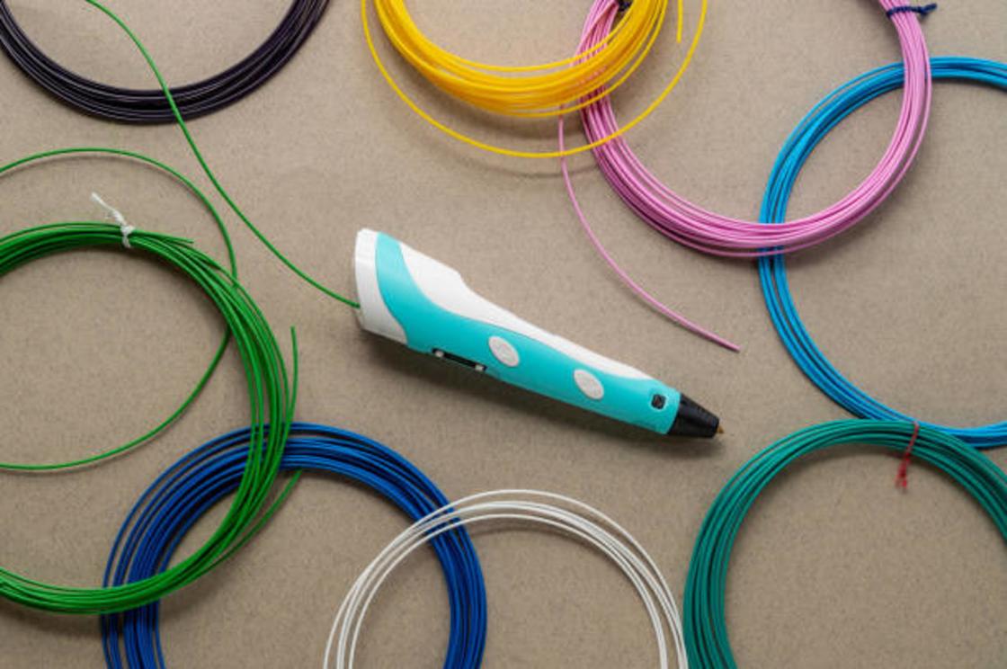 3D ручка и разноцветные пластиковые нити лежат на столе
