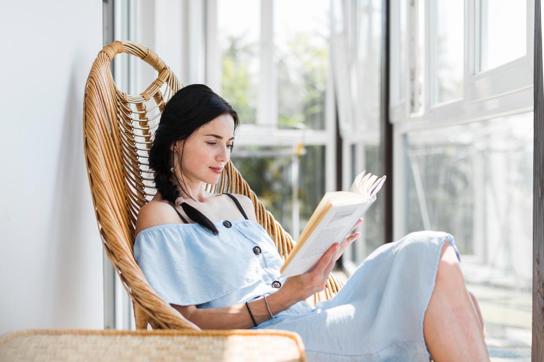 Женщина читает книгу, сидя в кресле