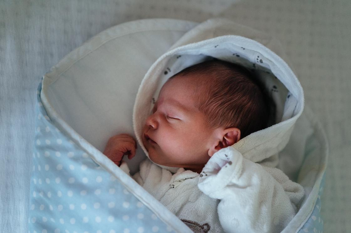 Новорожденный спит в конверте